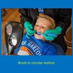 staff member brushing a patient's teeth in a circular motion