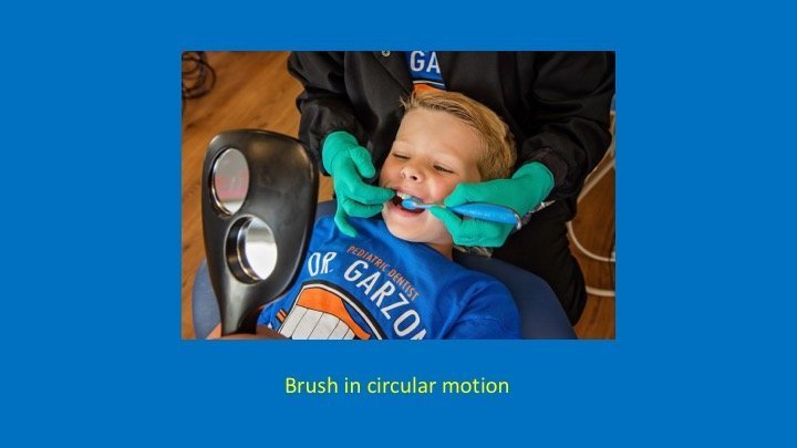 staff member brushing a patient's teeth in a circular motion